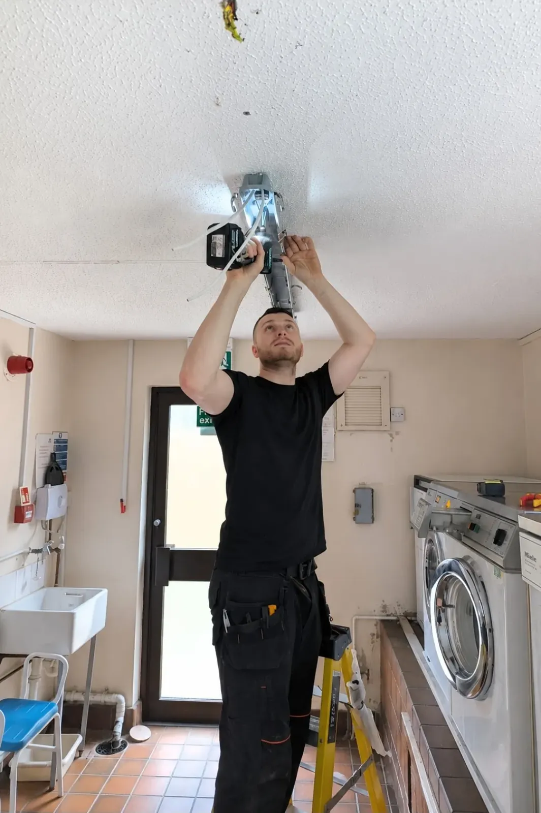 Dan Payne of PowerOn Electrical Engineering fitting a ceiling light