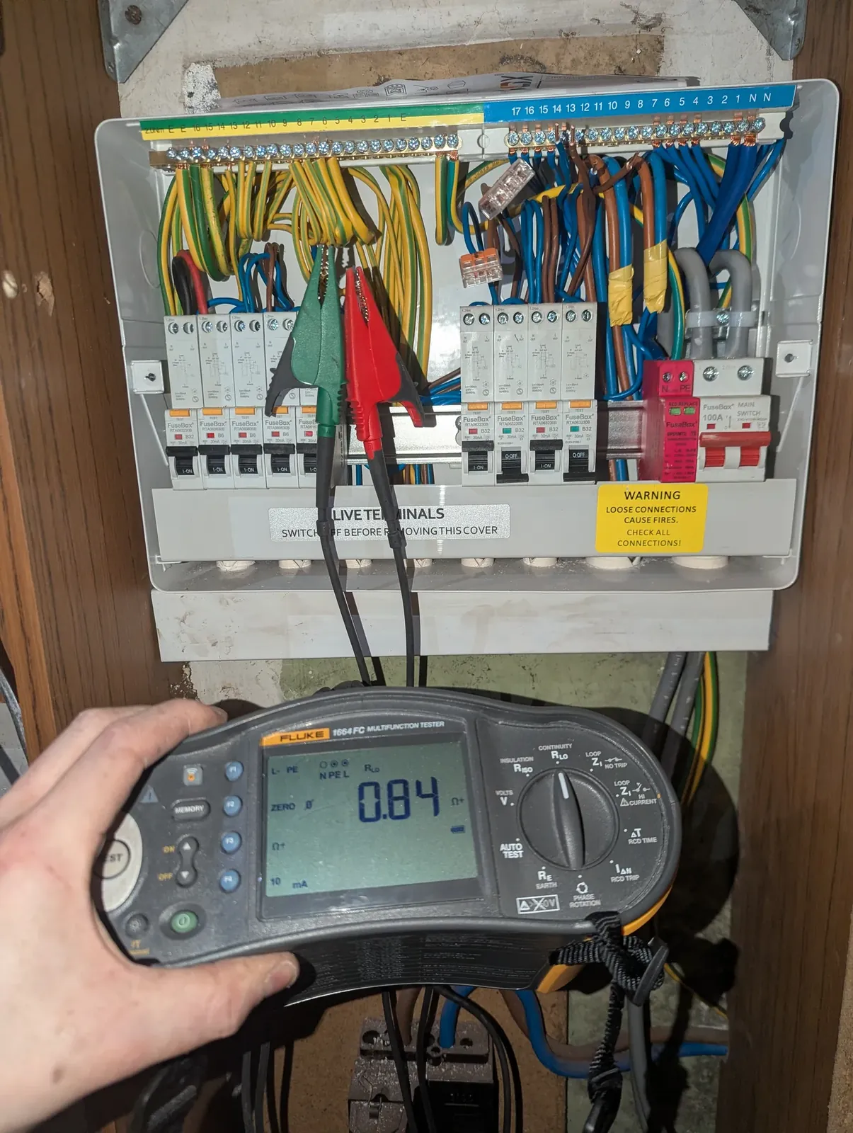 Fluke multifunction tester in front of an open RCBO consumer unit during an EICR