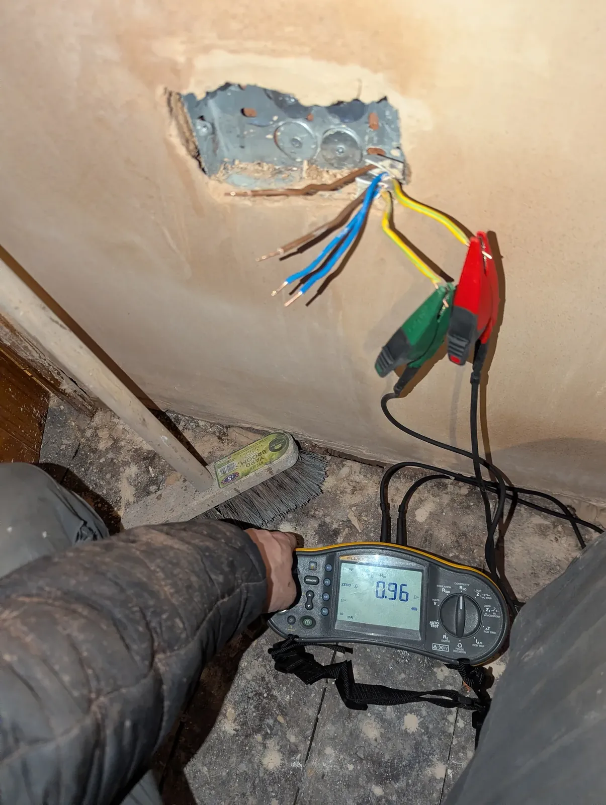 Tester connected to conductors in a wall back box during an inspection