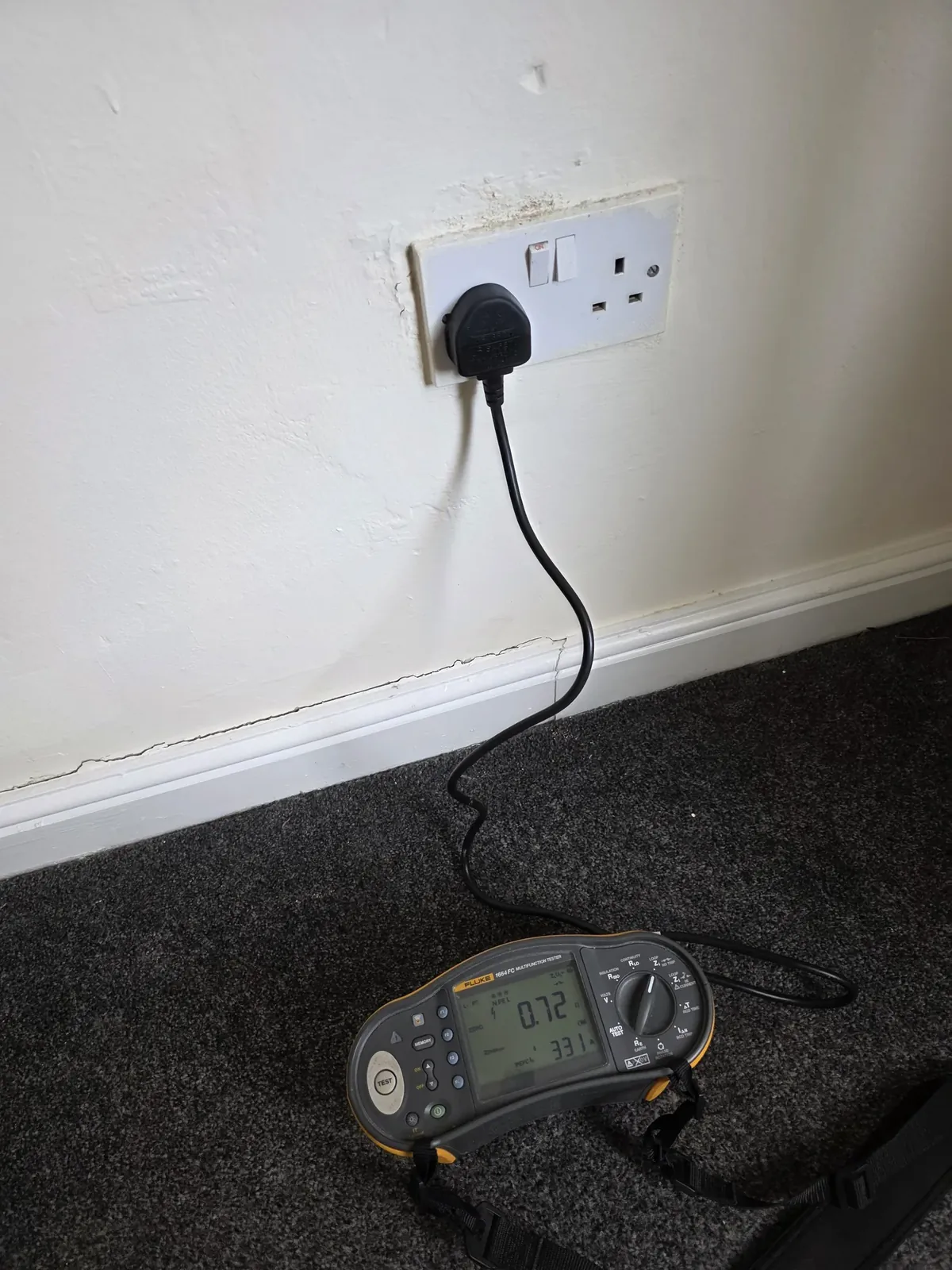 Fluke multifunction tester plugged into a double socket via its mains test lead
